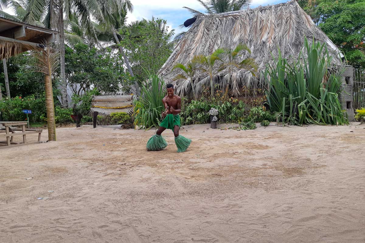 A fijian man does a traditional dance in a green outfit robinson crusoe island fiji