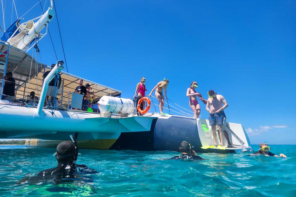A photo from the water looking at the Sabre catamaran as people in snorkel gear get ready to jump in Fiji