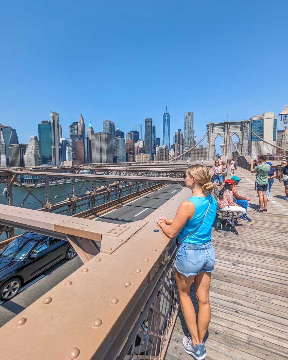 Bailey admires Manhattan from the Brooklyn Bridge Walkway in summer in NYC