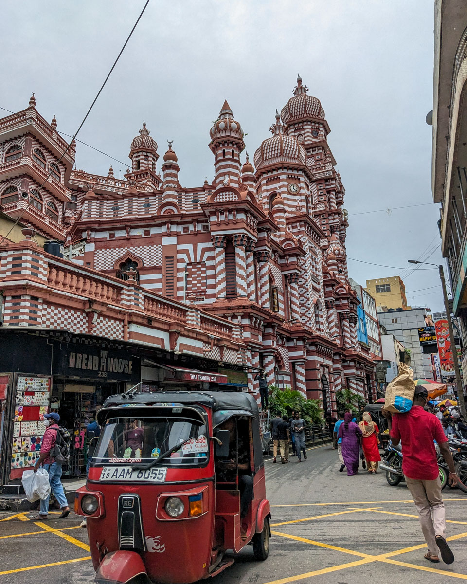 Looking at the red and white patterend Jami Ul-Alfar Mosque from down the street while a tuktuk drives by Colombo, Sri Lanka