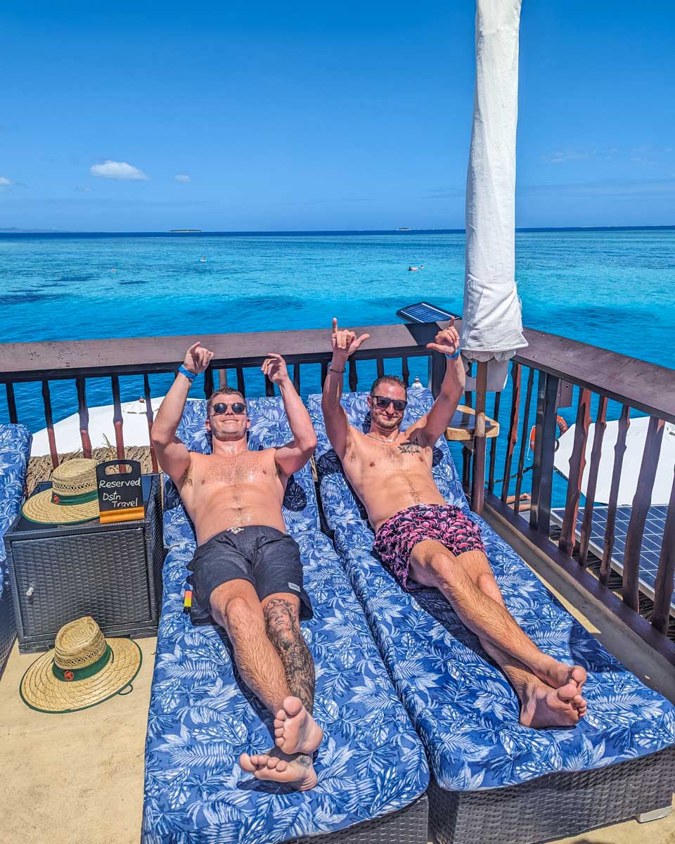 Two people relax on day beds at Seventh Heaven Fiji floating platform