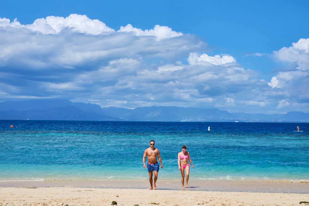 Two people walk out of the water at the beach on Malamala Beach Club