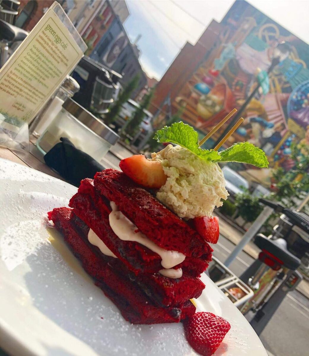 a red cake pastry stacked with fruit and cream on the patio at Green Eggs Cafe