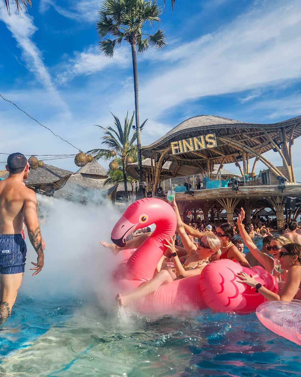 A group of ladies float on a pink flamingo at Finns Beach Club in Canggu, Bali