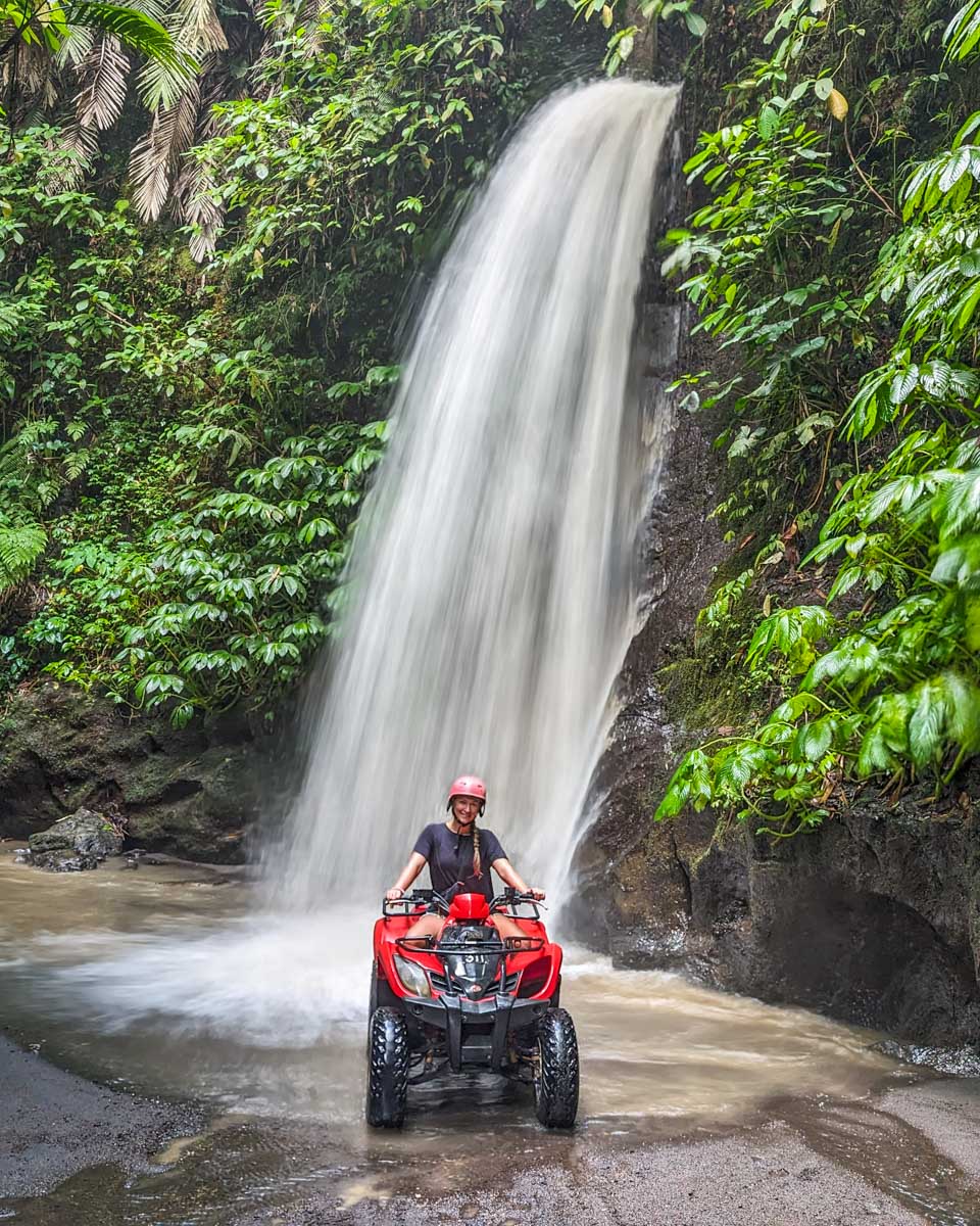 Bailey on an ATV tour poses for a photo in front of a waterfall in Bali
