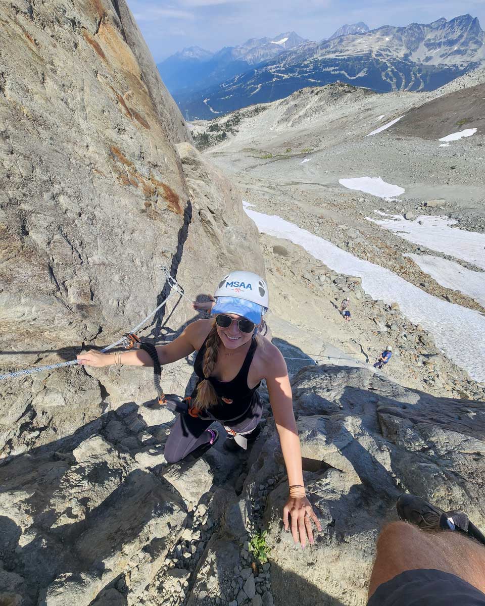 Bailey smiles as she climbs up rocks during Via Ferrata, Whistler, Canada