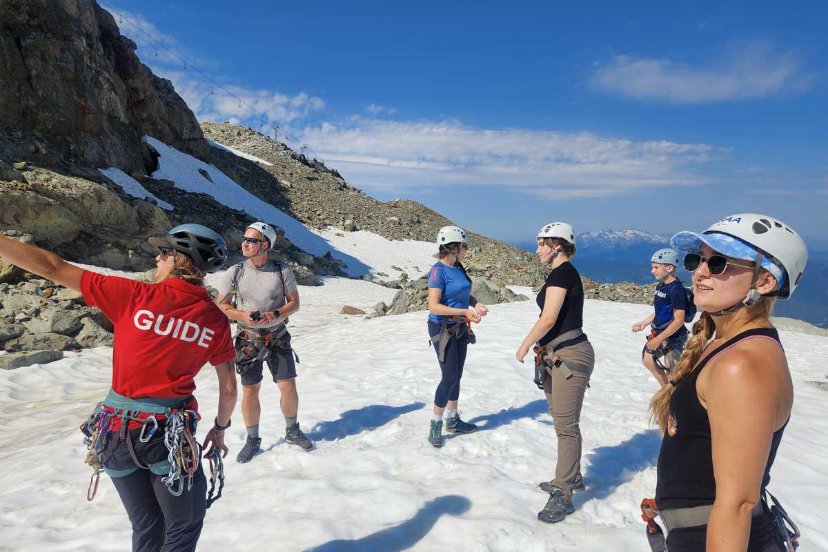 Bailey stands in the snow on whistler listening to a guide during Via Ferrata, Whistler, Canada