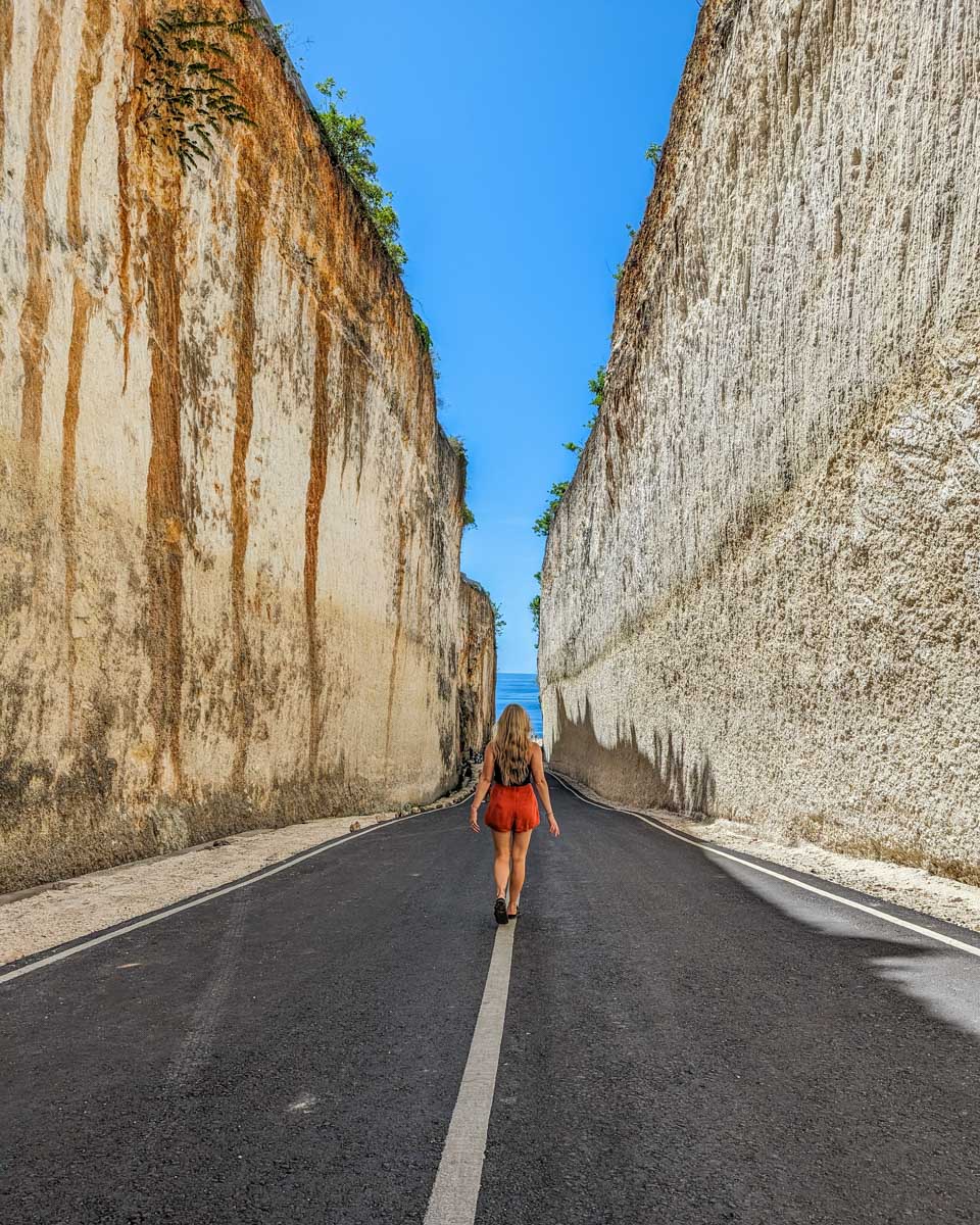 Bailey walks on the road below the Tanah Barak Cliff  in Uluwatu, Bali