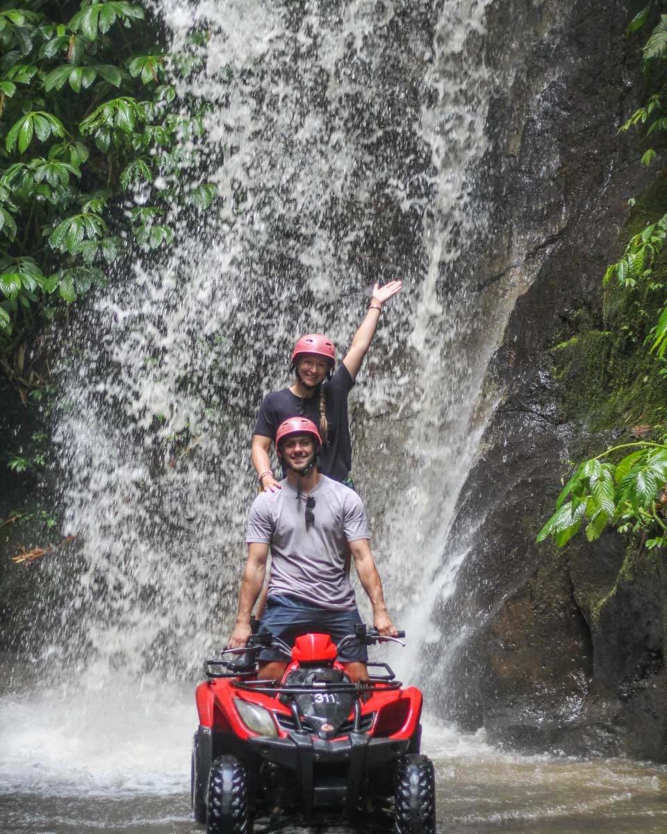 Daniel and Bailey on an ATV tour in front of a waterfall in Bali