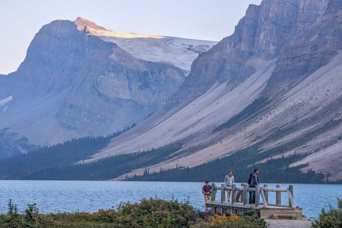 People cross a wooden bridge at Bow Lake