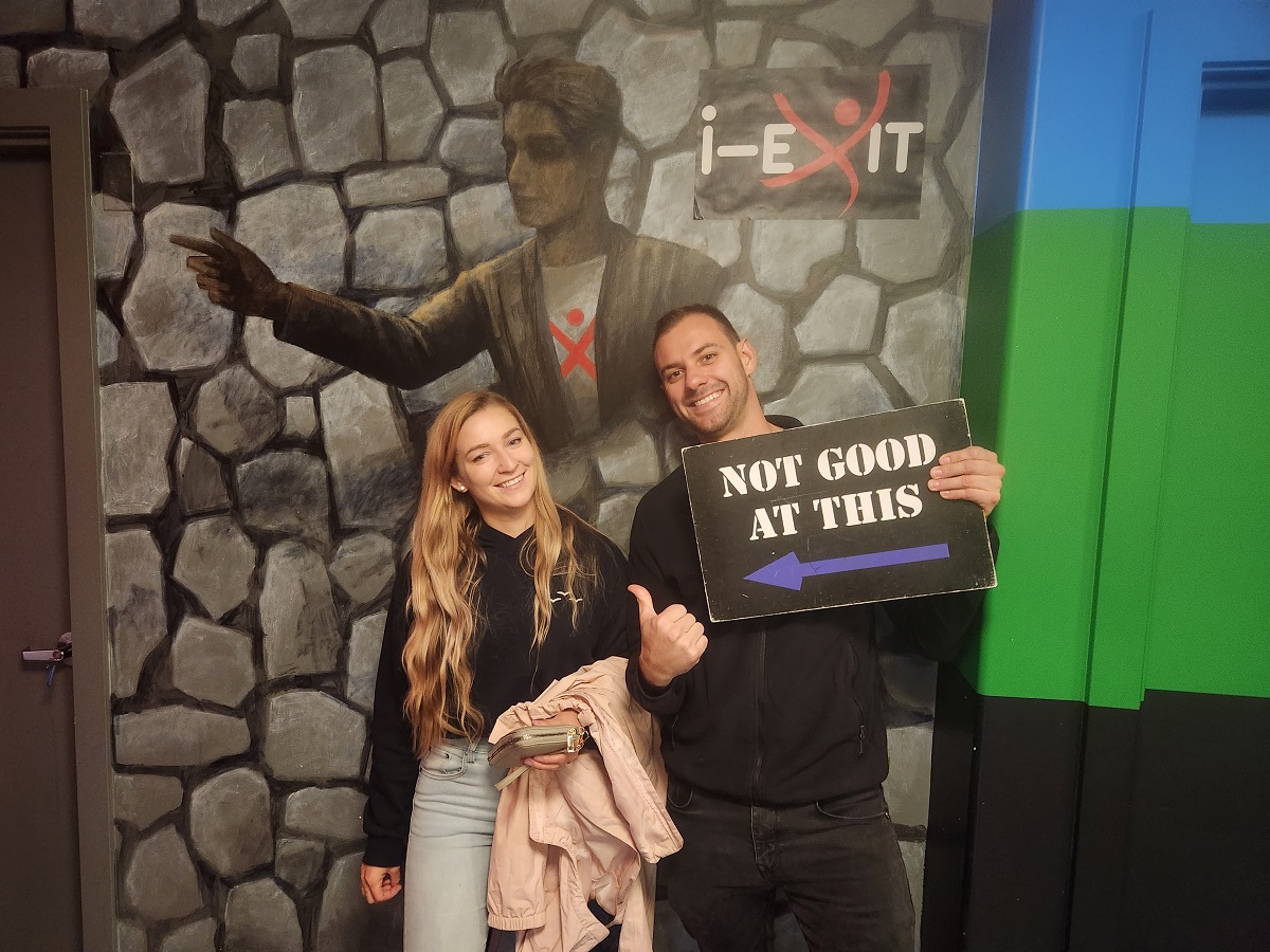 Bailey and Daniel pose with a sign at the i-Exit escape room in Vancouver