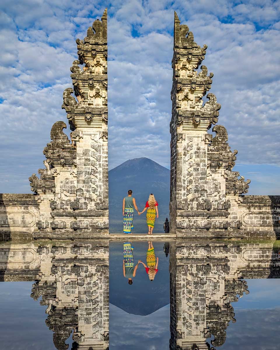 Bailey and Daniel at the gate to Lempuyang temple with the mountain in the distance on the instagram tour bali