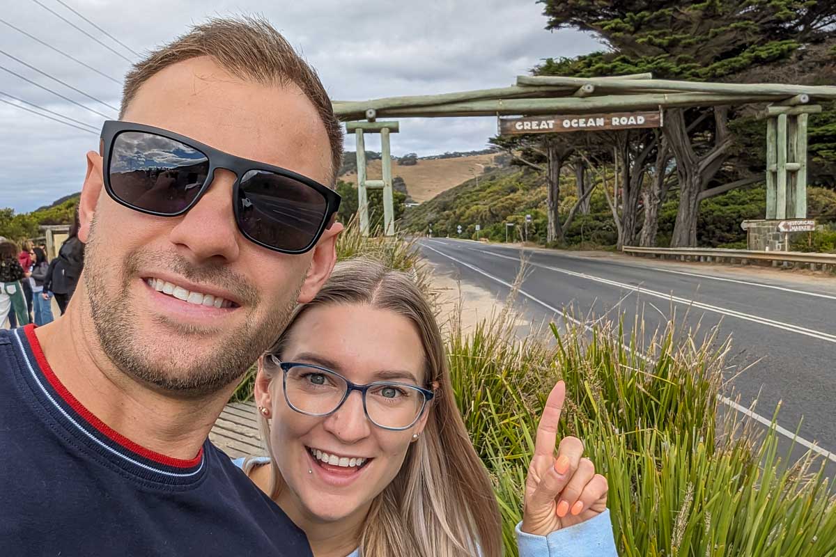 Daniel and Bailey pointing at a sign signiling the start of the great ocean road australia