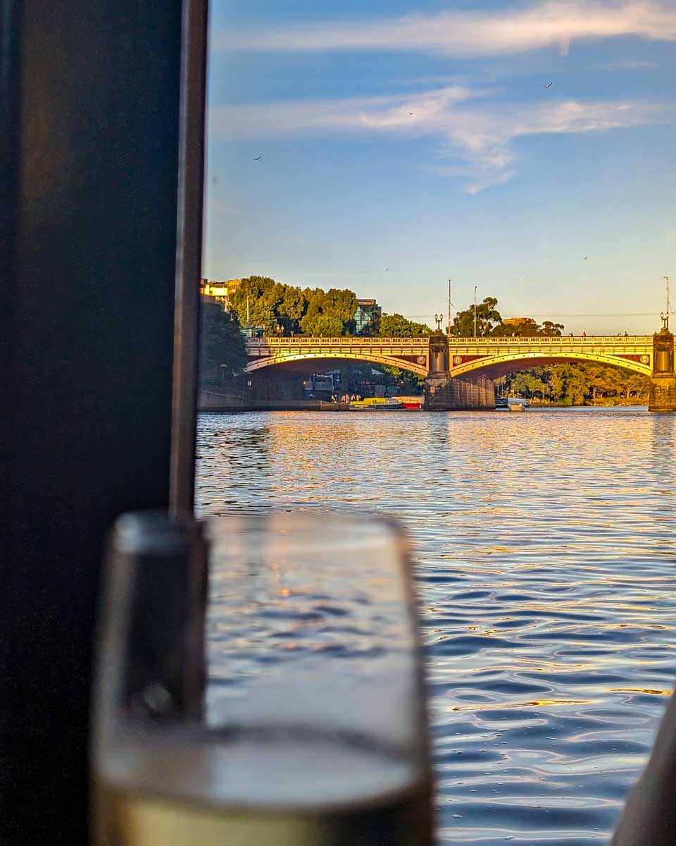 wine glass on the spirit of melbourne dinner cruise with a bridge in the background