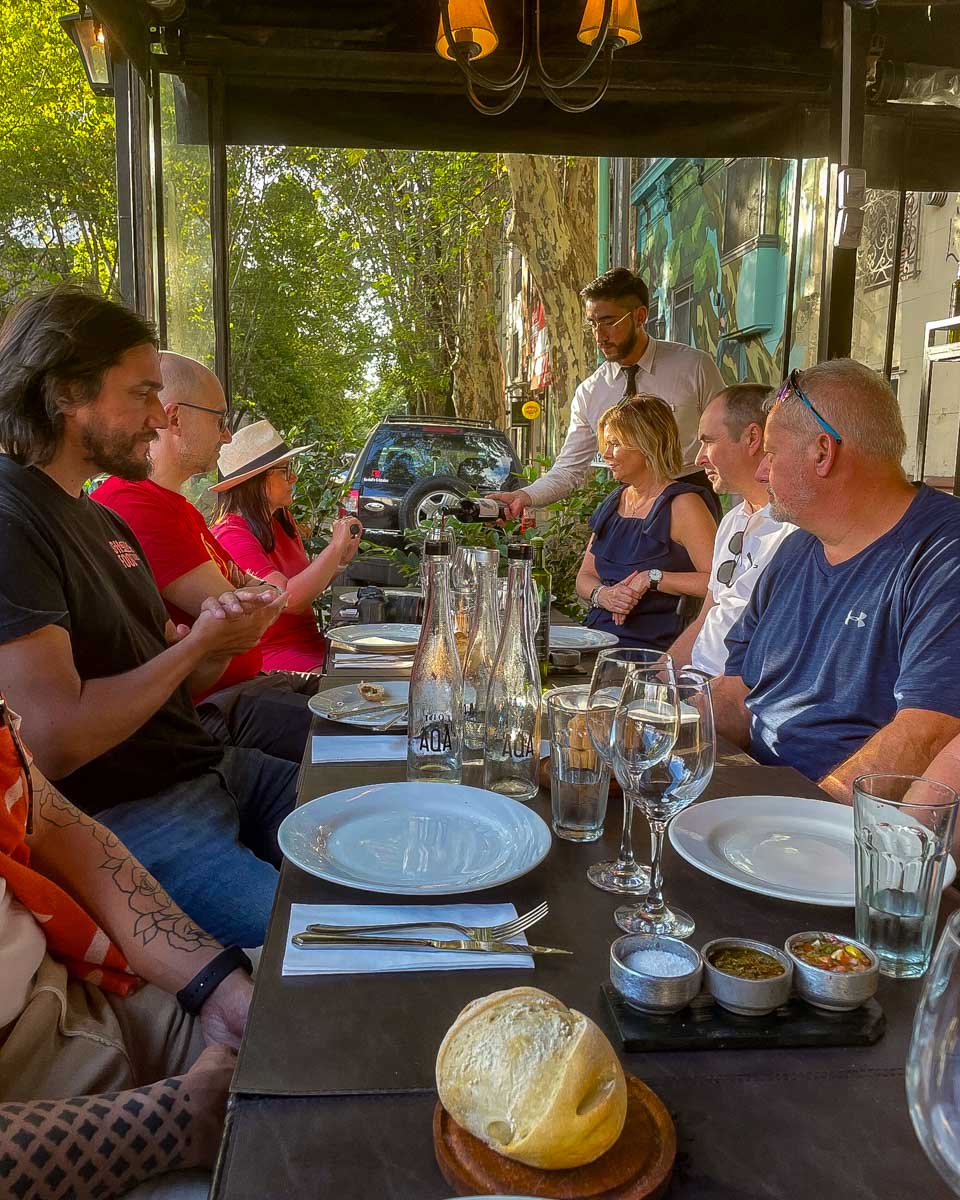 People listen to a guide and wait for their meal on a sherpa food tour in Buenos Aires Argentina