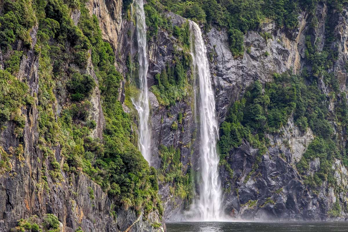 The side of the Milford Sound fjord and big waterfall on a cruise New Zealand