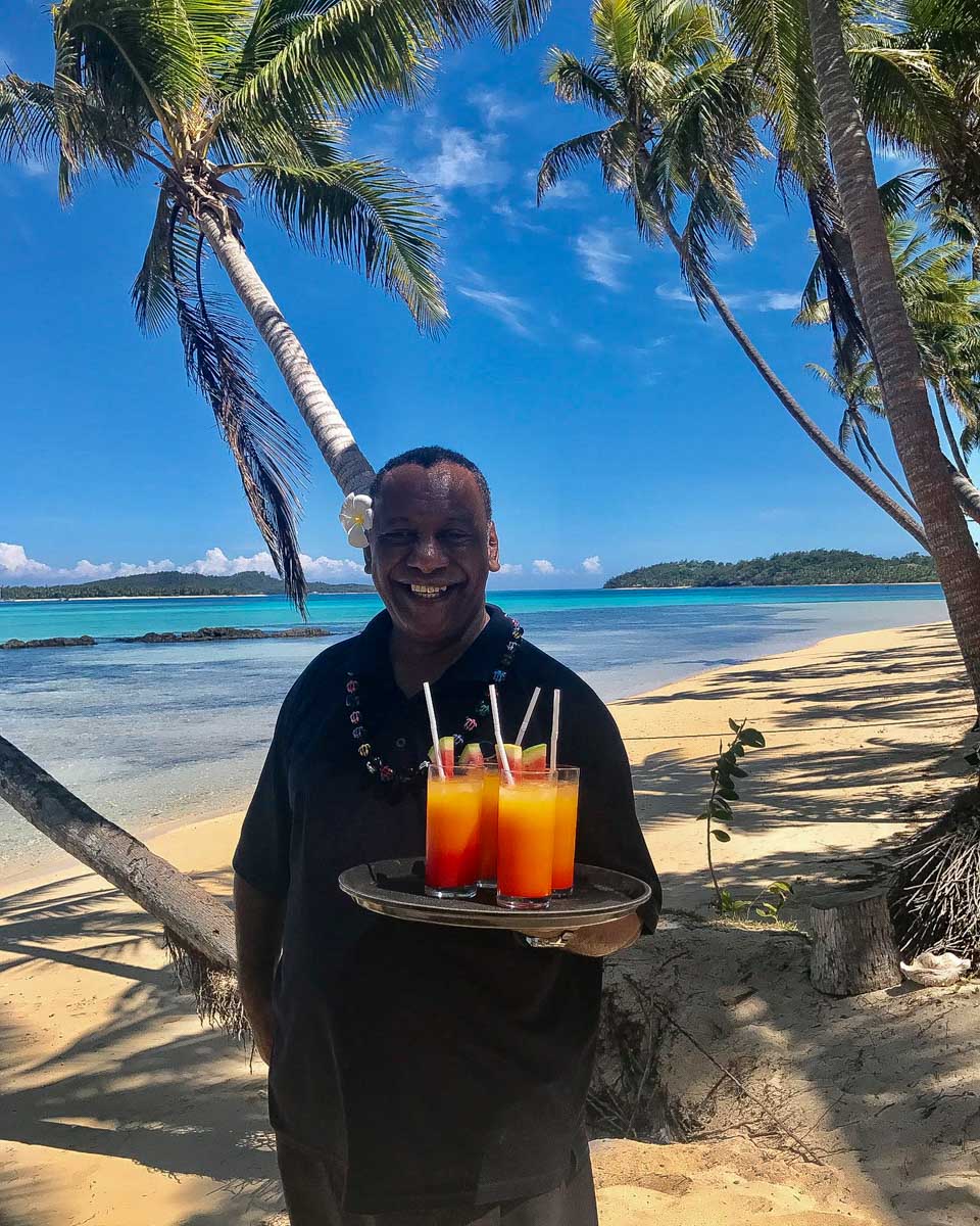 A Fijian Man holds drinks on the beach at Coconut Beach Resort Fiji