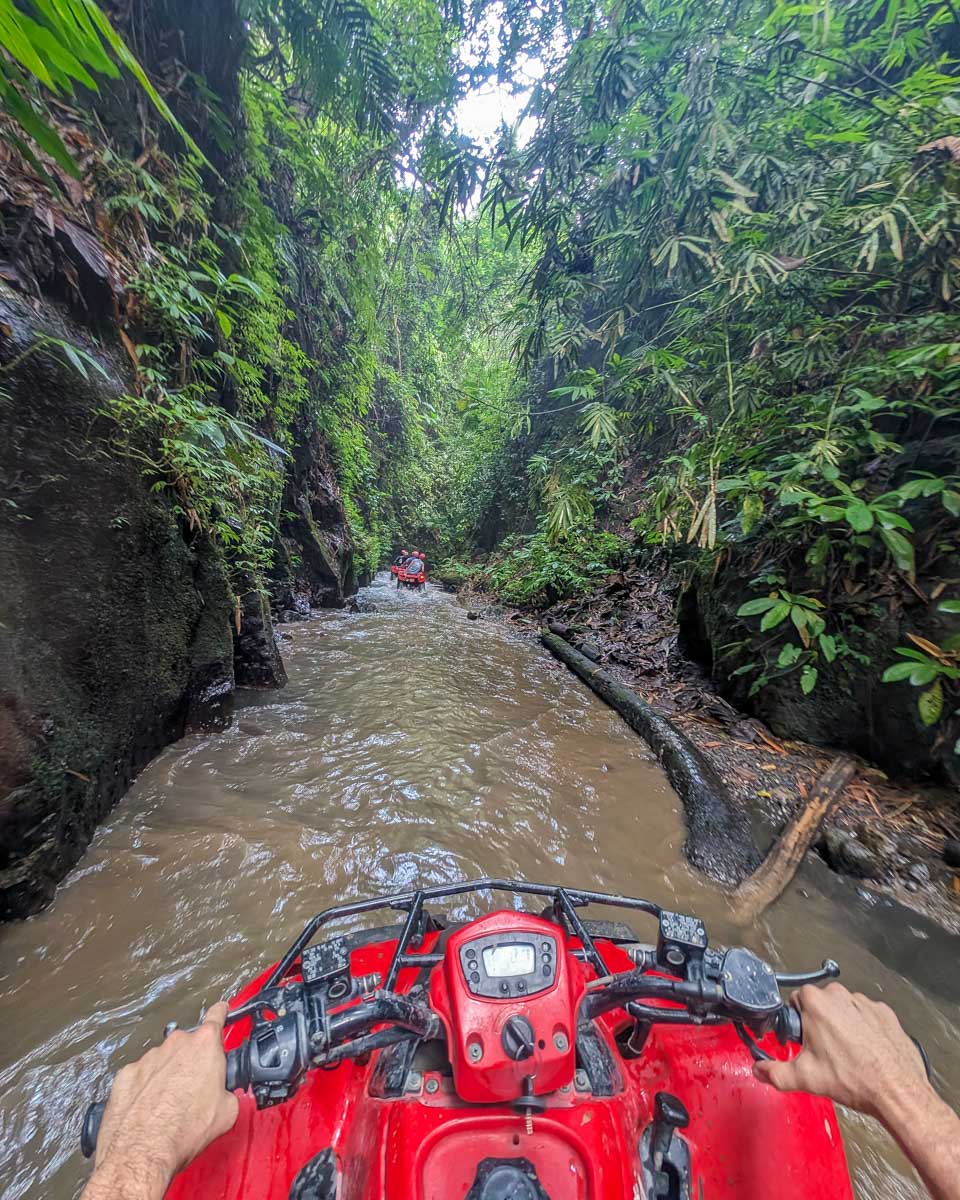 A person drives an ATV through the water on an ATV tour in Bali