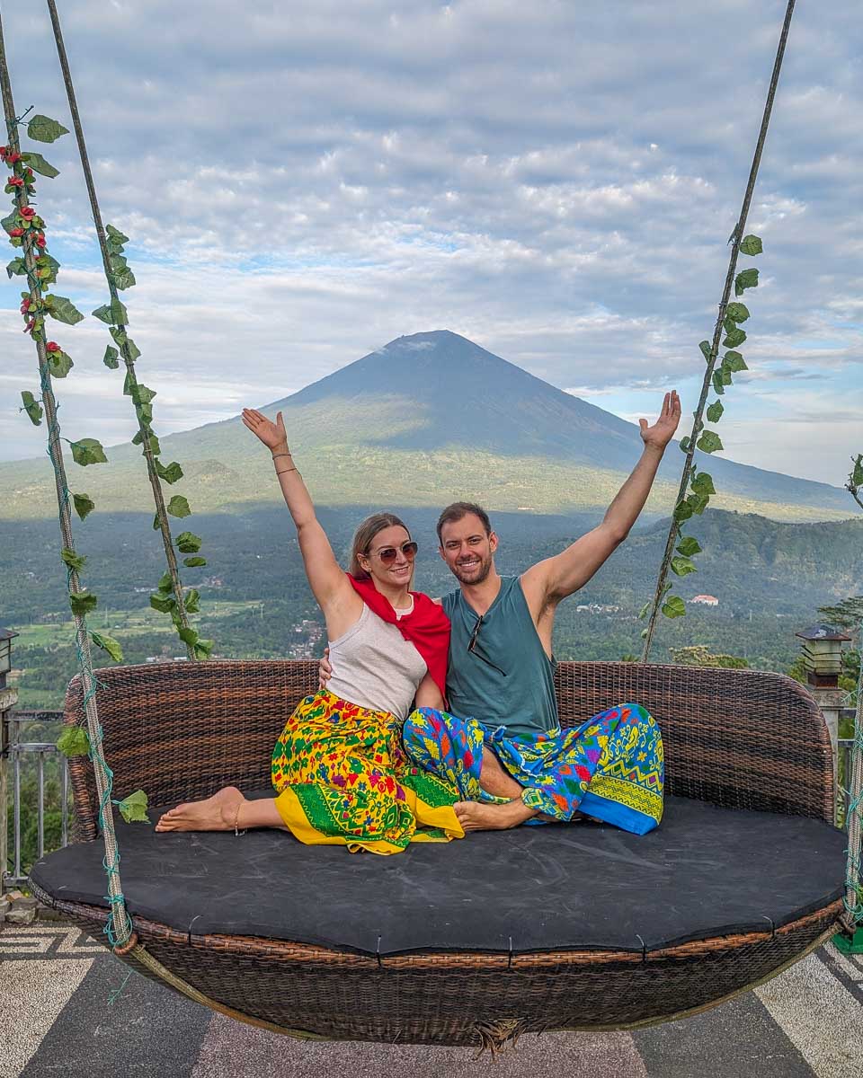 Bailey and Daniel on a swing with Mount Agung in the background at Lempuyang temple Bali