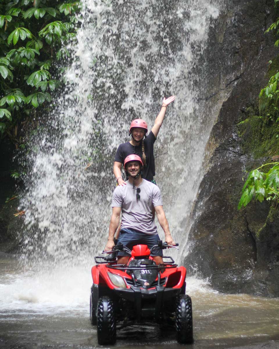 Daniel and Bailey on an ATV tour in Bali by a waterfall
