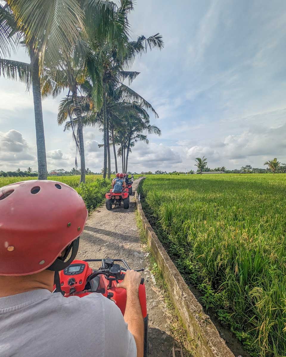 Daniel driving an ATV by a field in Bali on a tour