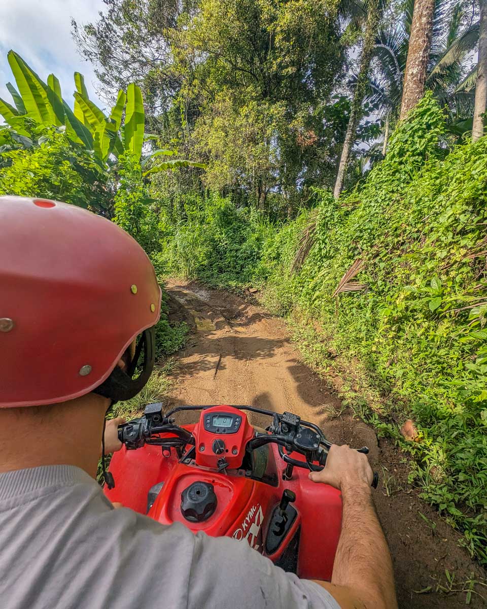 Daniel driving an ATV down a dirt road in Bali on a tour