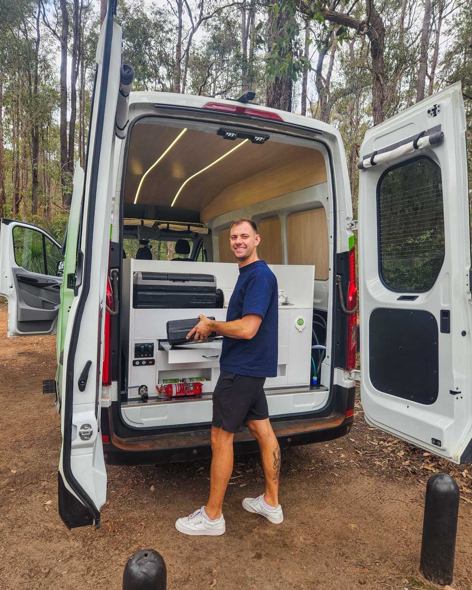 Daniel stands in the woods with a JUCY campervan in Australia