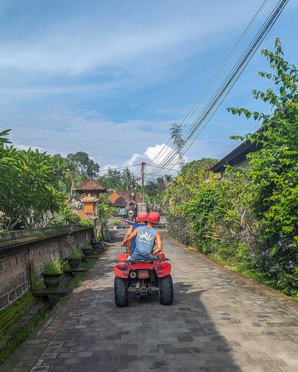 People ride on an ATV through a town in Bali on a tour