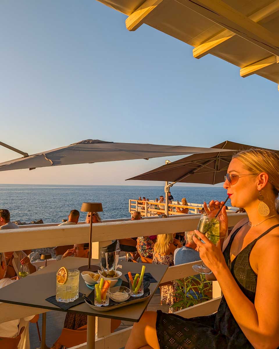 Bailey drinks aperitif at sunset with views of the water Cefalu Italy
