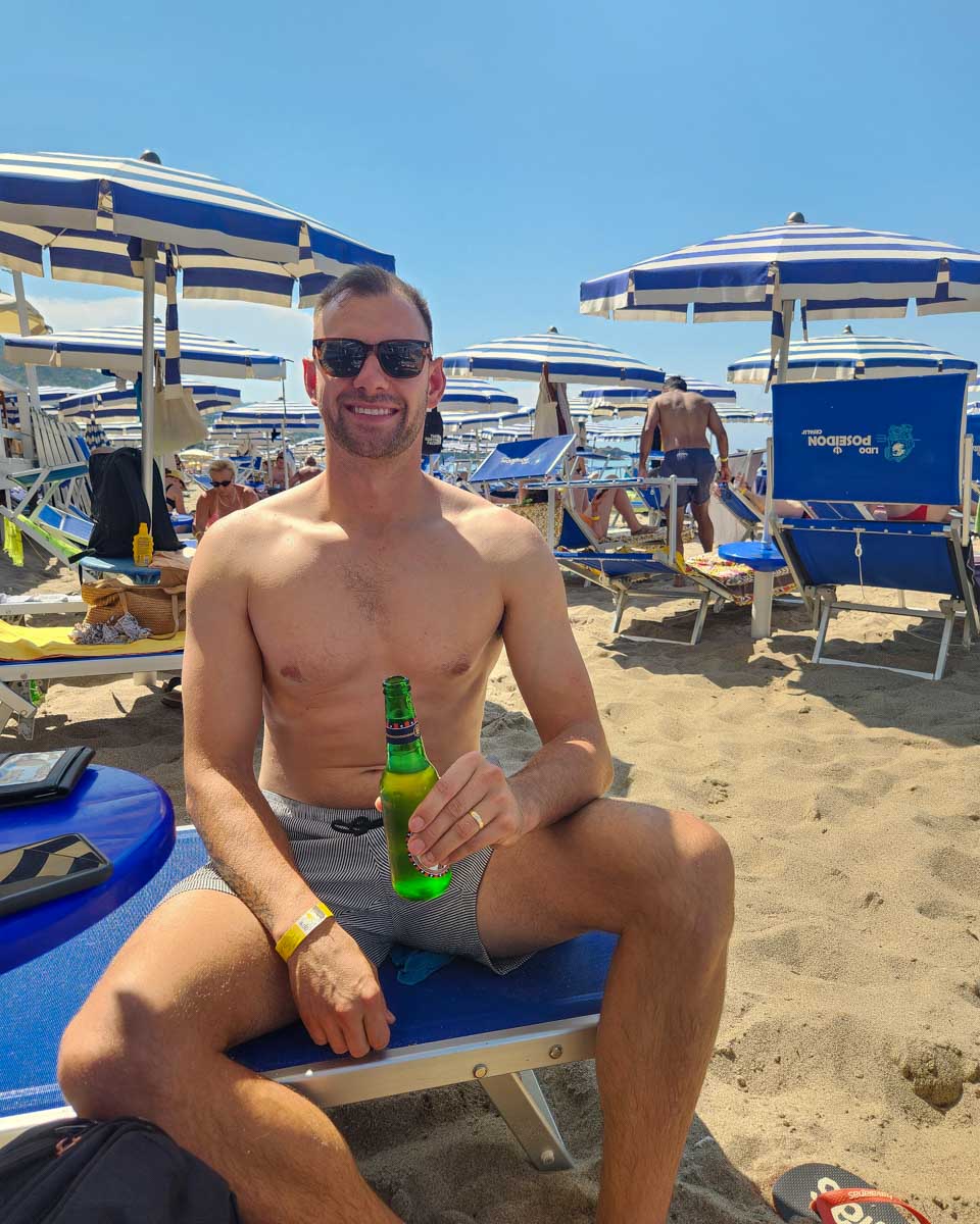 Daniel at the beach drinking a beer in Cefalu Italy