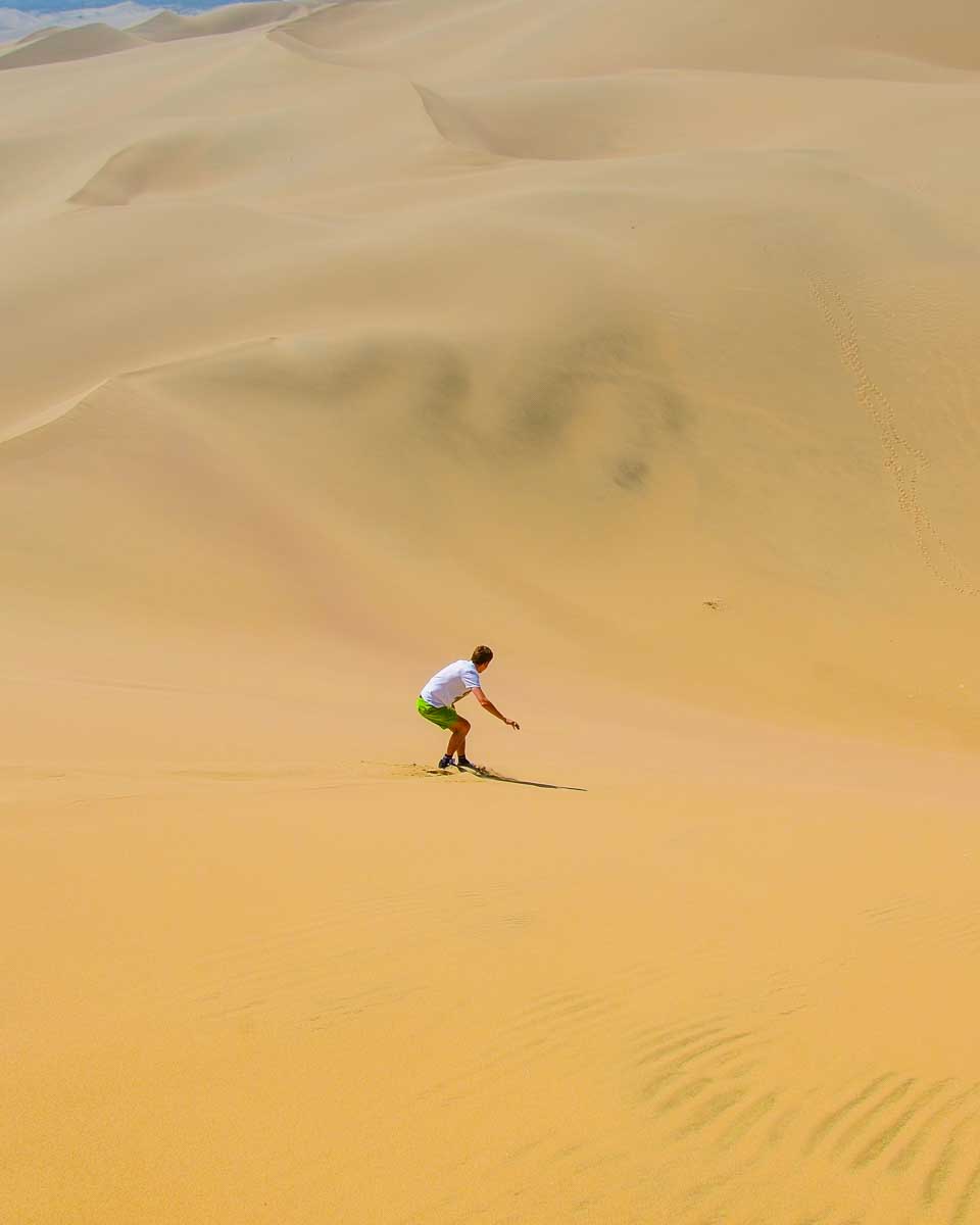 A person sand boards at Huacachina Oasis Peru