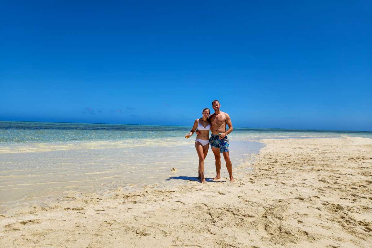 Bailey-and-Daniel-posing-for-a-picture-on-a-sand-bar-with-turquise-blue-water-around-them-Curacao