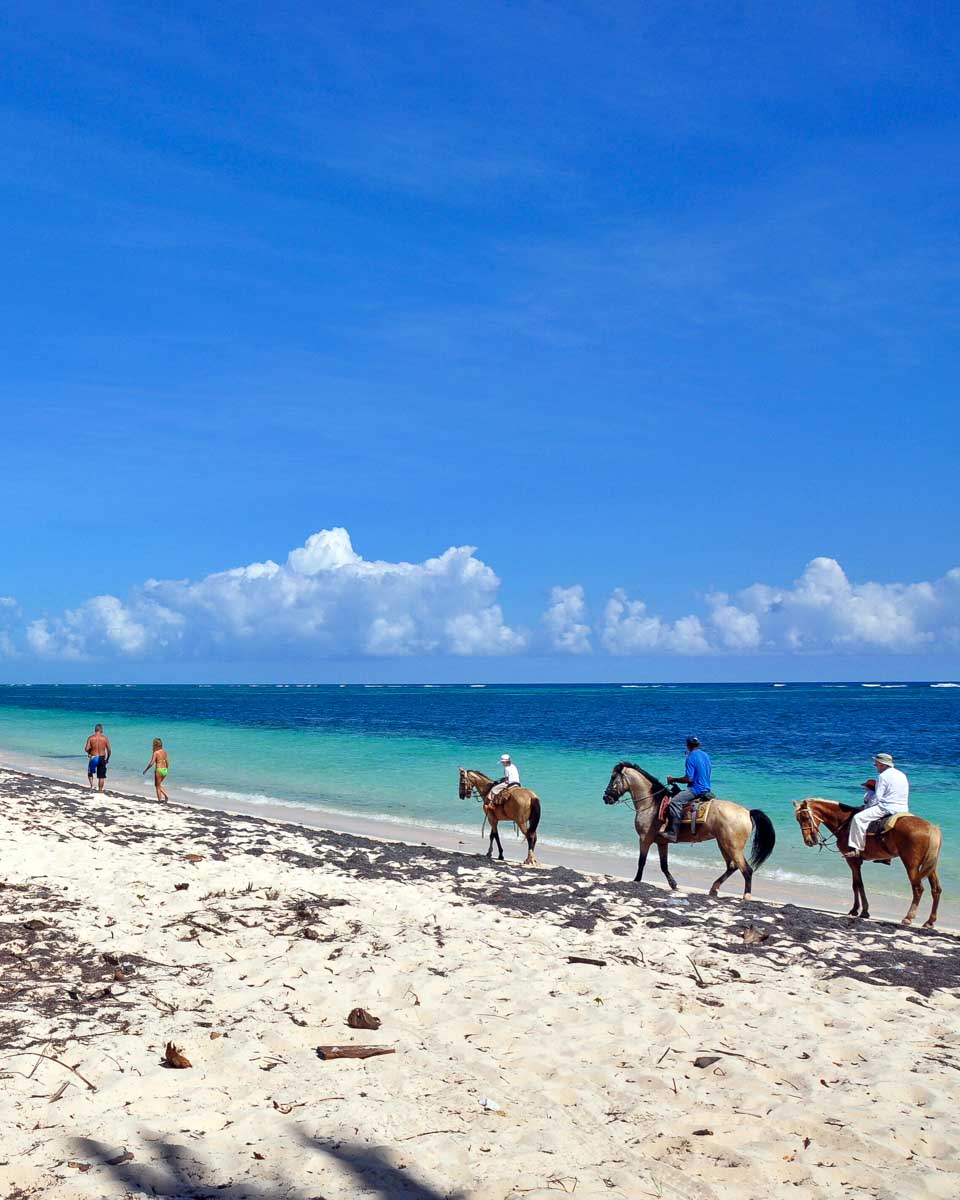 People ride horseback on a beach in Punta Cana Dominican Republic