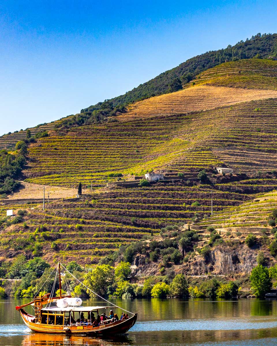 A boat travels down the Douro Valley River on a tour from Porto Portugal