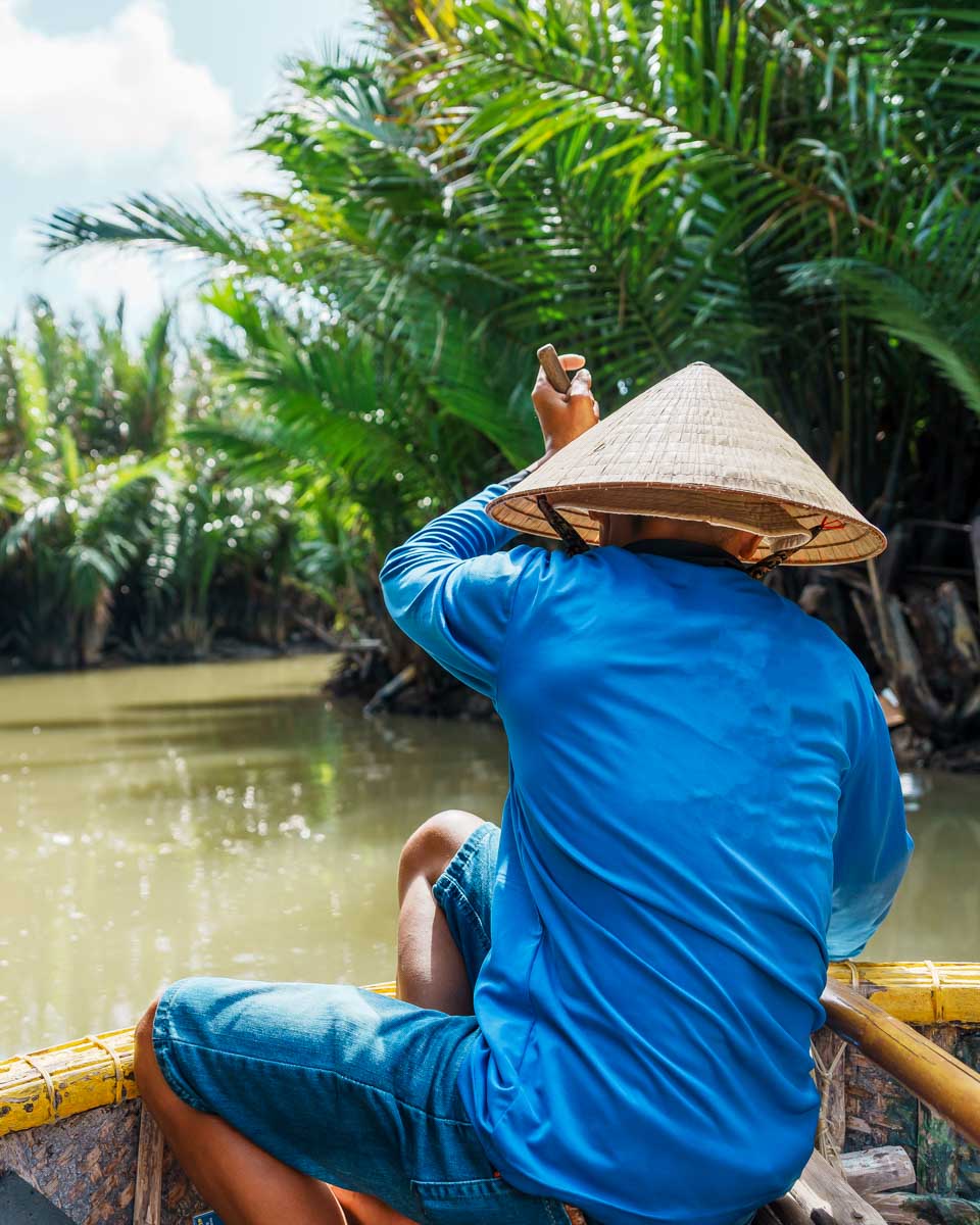 A man pushes a basket boat down the river in Hoi An Vietnam