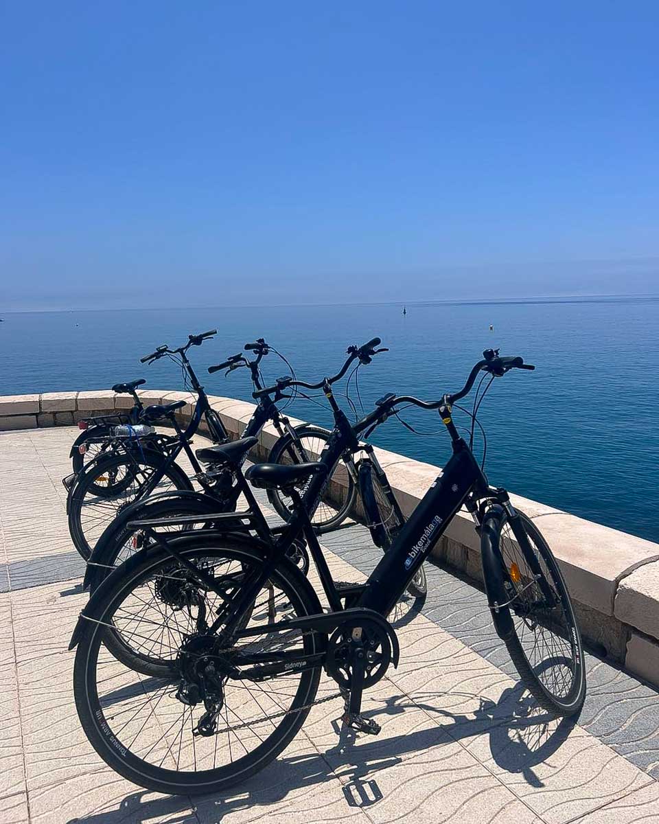 Four ebikes parked along the seawall in Malaga, Spain