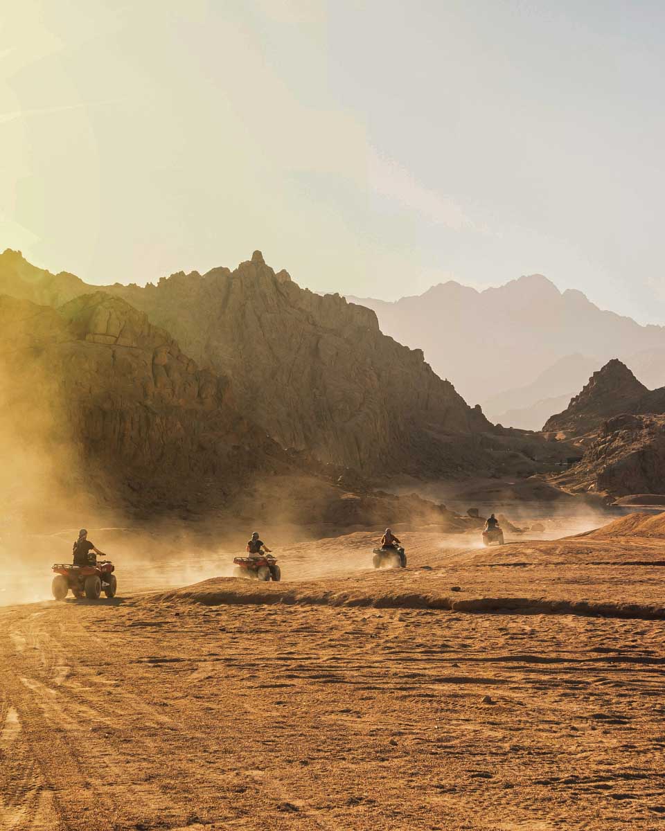 People-ride-through-the-desert-at-sunset-on-atvs-on-a-tour-from Hurghada Egypt