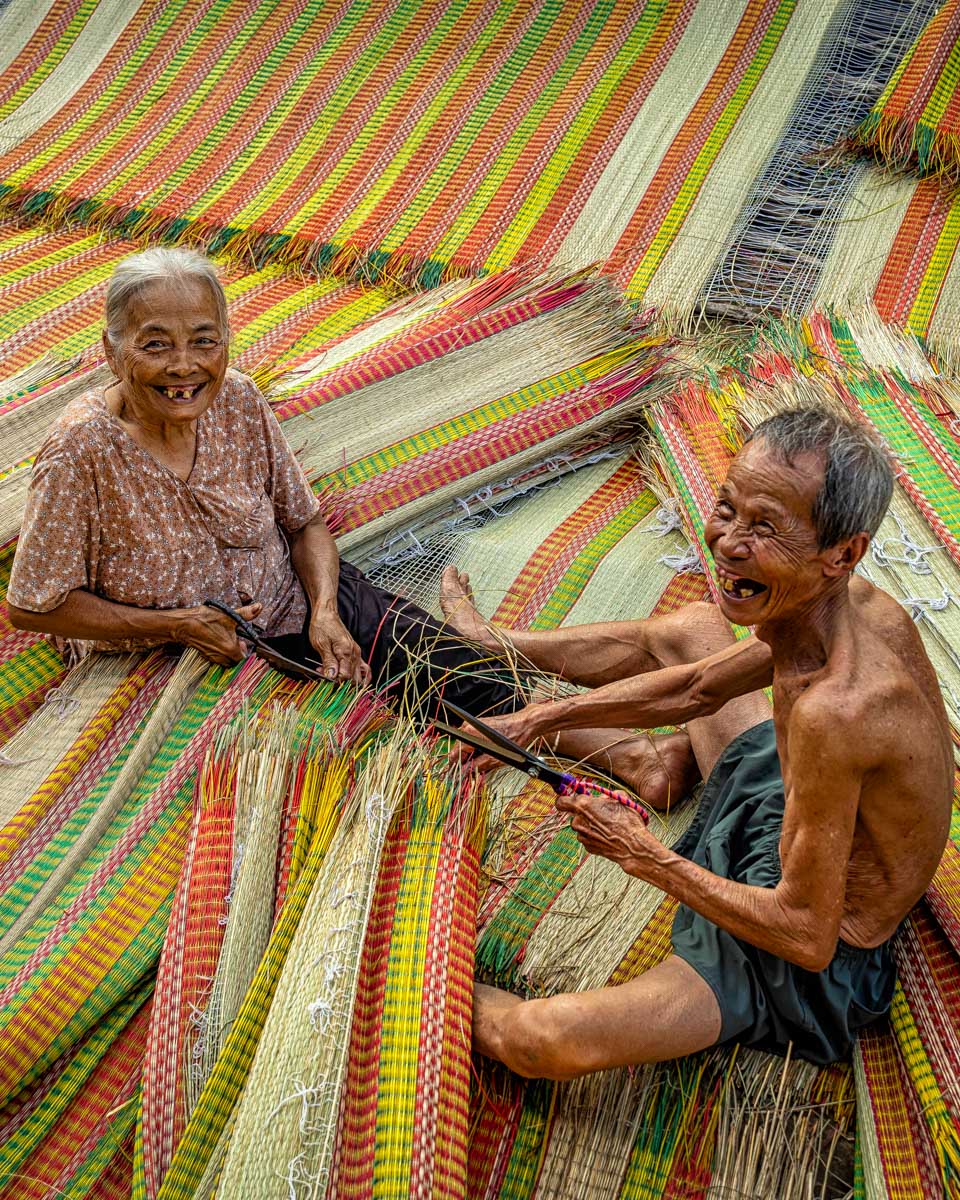 Two people make traditional mats on a bike tour from Hoi An Vietnam