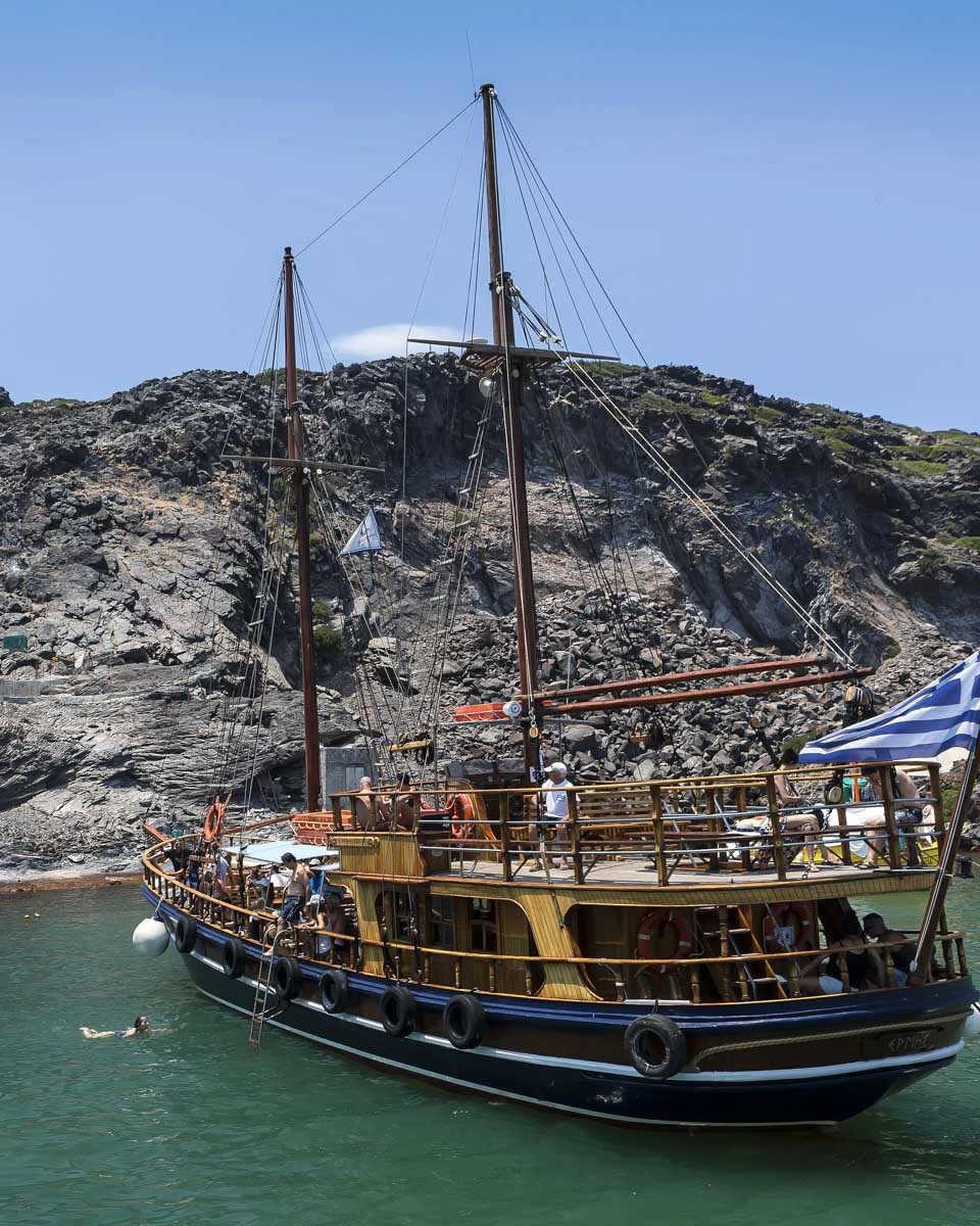 A traditional sailboat floats at Palea Kameni hot springs on a tour from Santorini Greece