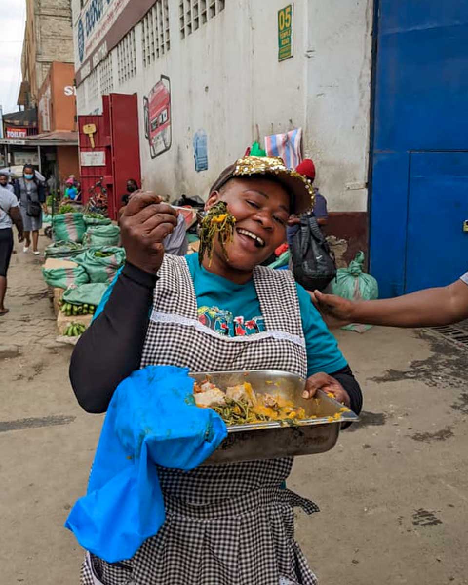 Nai Nami a woman smiles and holds food on a street tour of Nairobi Kenya