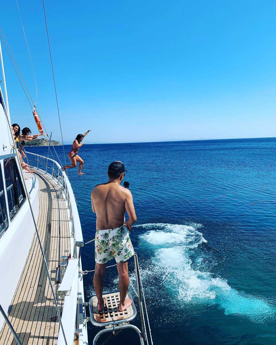 People jump off the boat on a boat trip from Mykonos Greece