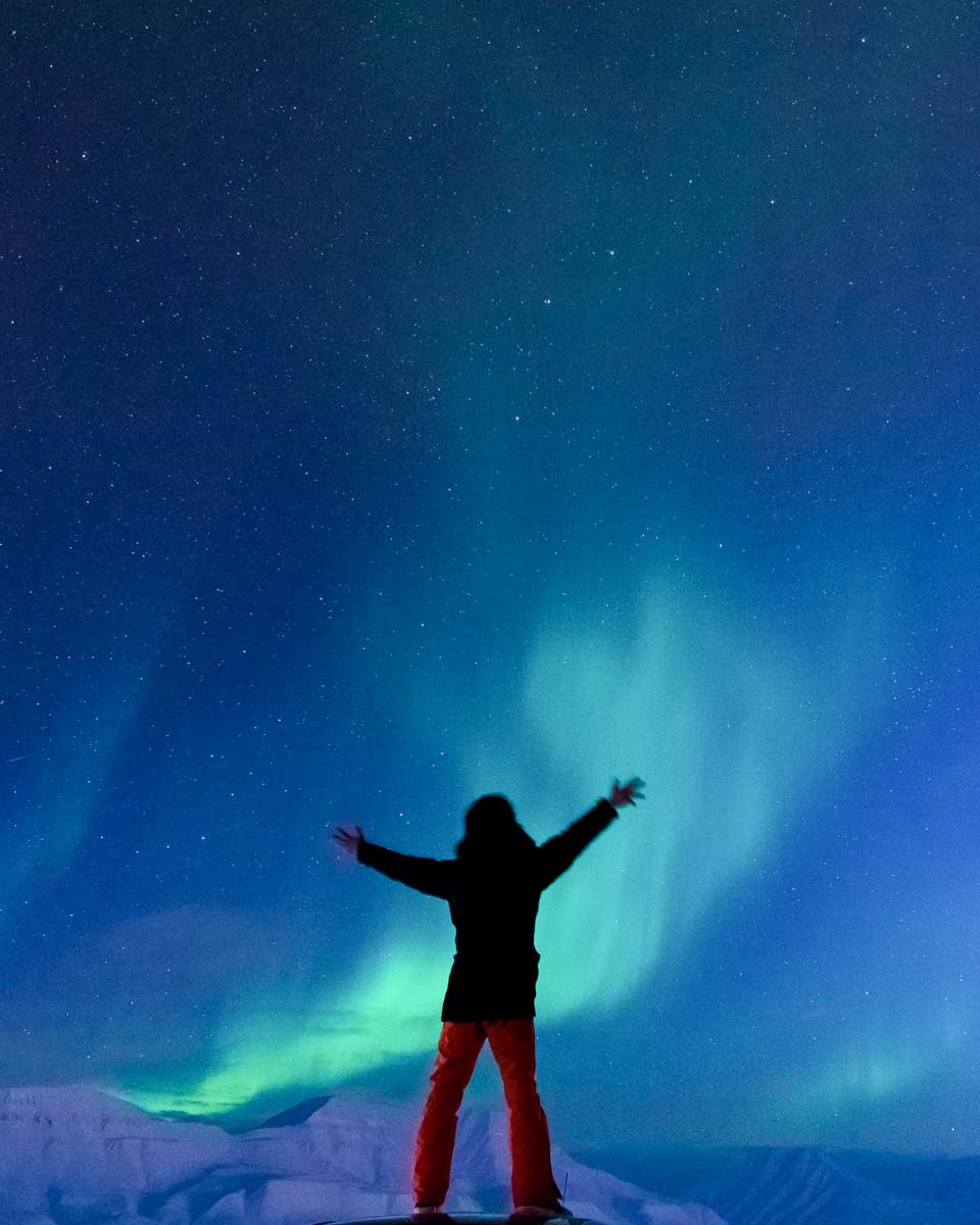 A-person-stands-looking-at-Aurora-Northern-Lights-in-Reykjavik Iceland
