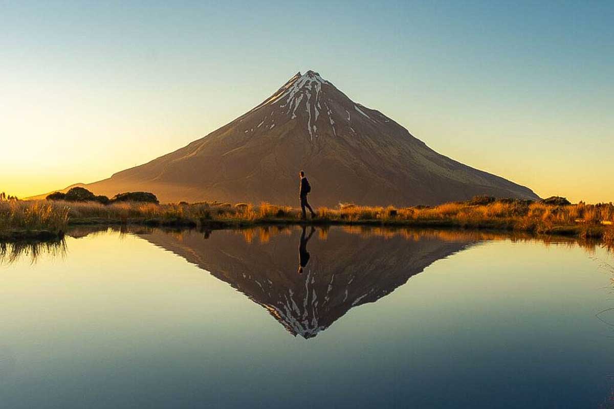 Dan walks in front of Mt Taranaki in New Zealand
