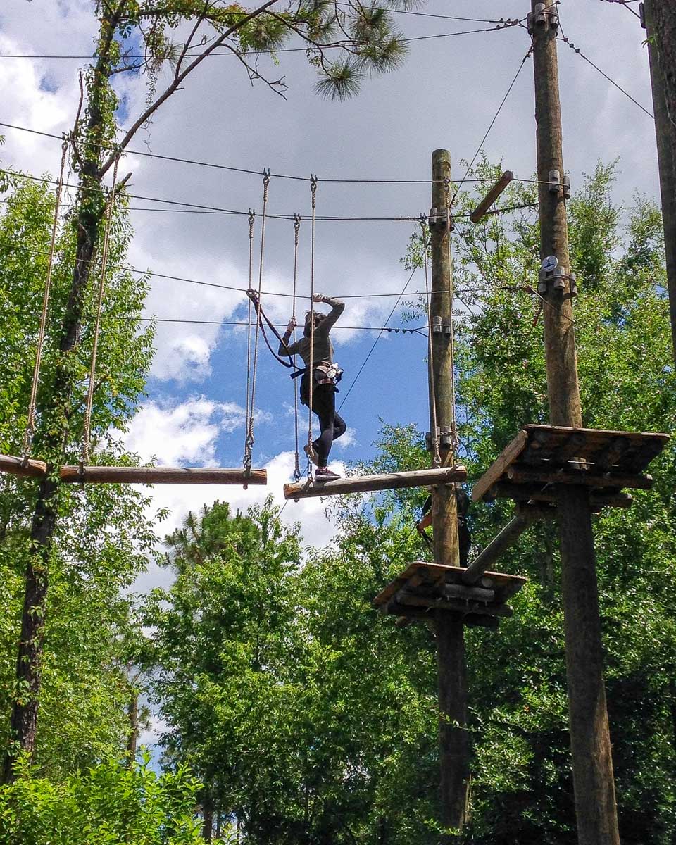 Orlando Tree Trek Adventure Park a woman crosses logs in the air in Orlando Florida