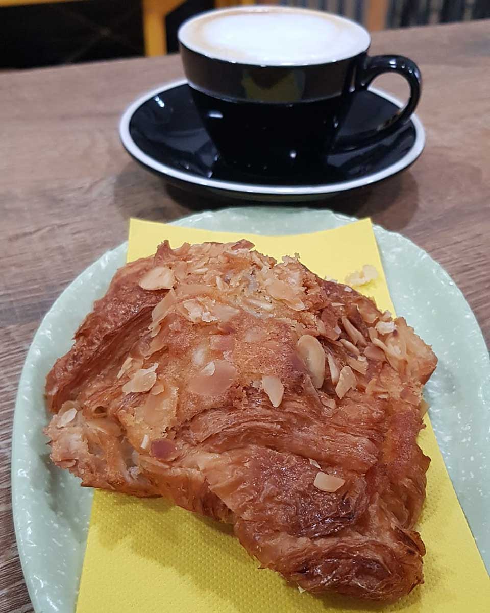 A coffee and almond croissant at Coffee Up in Seville Spain