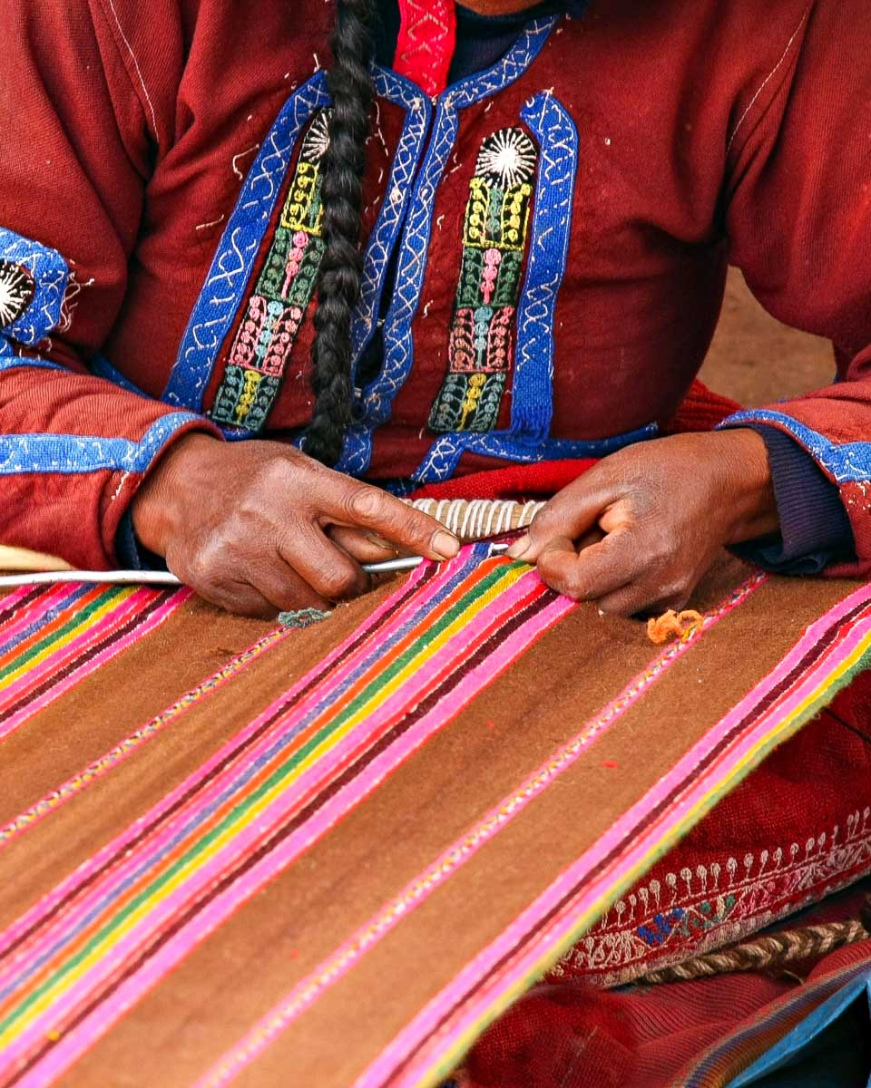 A local woman makes a blanket in Lucrepata Cusco Peru