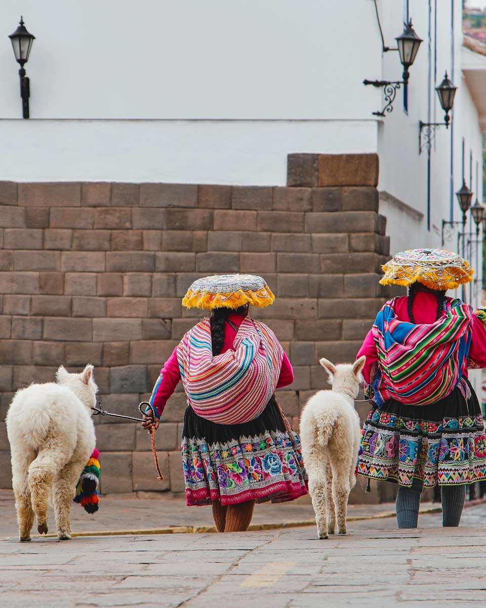 Two local women walk with llamas in Lucrepata Cusco Peru