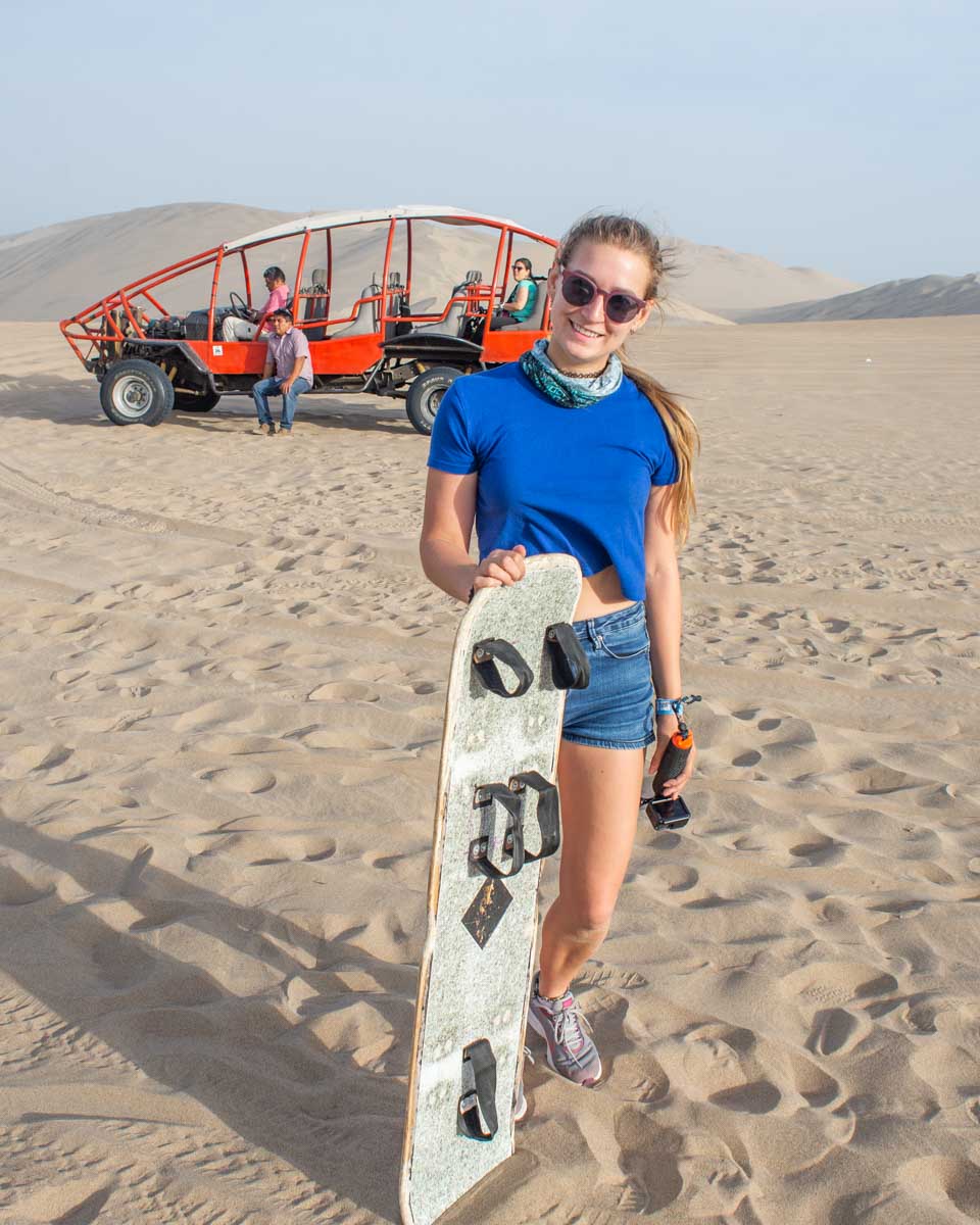 Bailey-poses-with-the-dune-buggy-and-sandboard-in-Huacachina-on a tour from Lima Peru