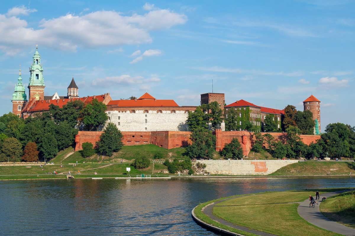 People walk along the river promenade near Wawel Royal Castle in Krakow Poland