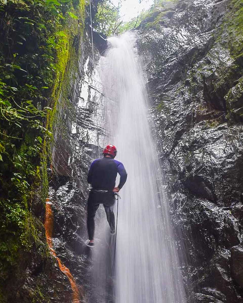A person rappels down a waterfall canyoning in Dominica